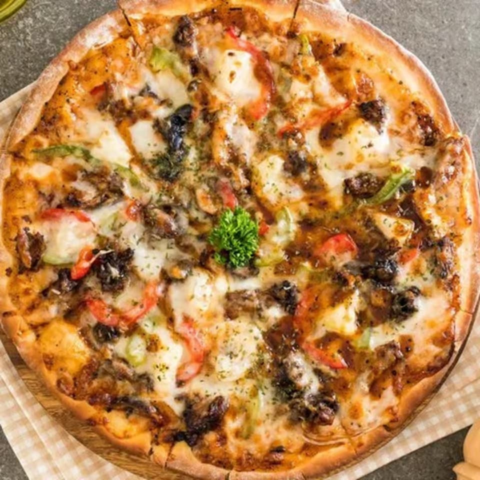 Milans Pizza & Wings' whole pizza, topped with cheese, vegetables, and a sprig of parsley.