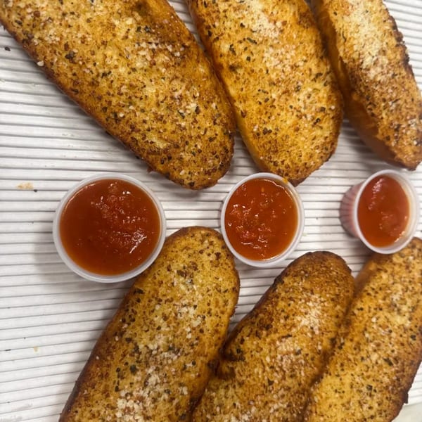 Golden-brown garlic breadsticks with parmesan cheese and three cups of marinara sauce.